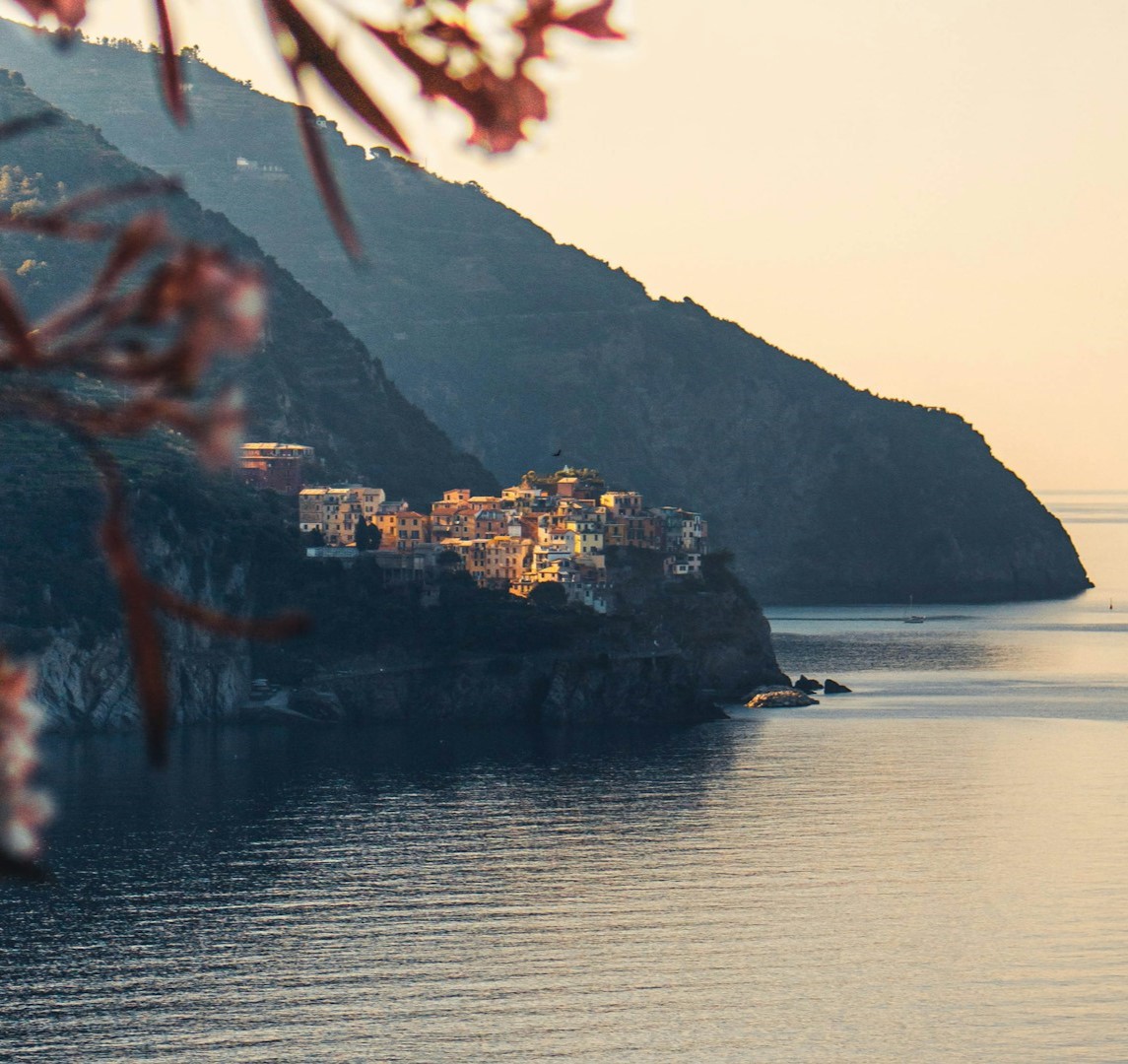 Cinque Terre October: An excellent time to visit due to milder temperatures, fewer crowds and warm water temperatures. View of one of the Cinque Terre towns in the distance