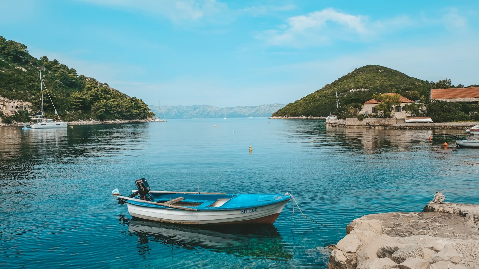 Boat floating in the Adriatic Sea with coastline and landscape of Mljet island in Croatia in the background