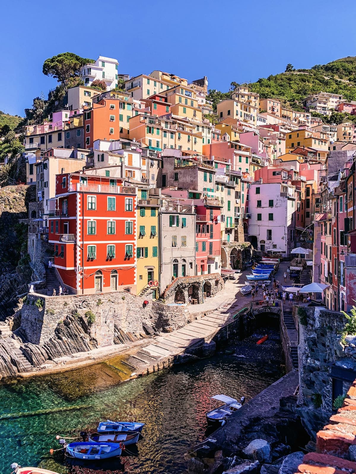 When considering where to stay in Cinque Terre, Riomaggiore is always a popular choice. A view of the Cinque Terre town of Riomaggiore with the small harbor in the foreground